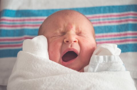 Neugeborenes schreiendes Baby in Decke gepuckt